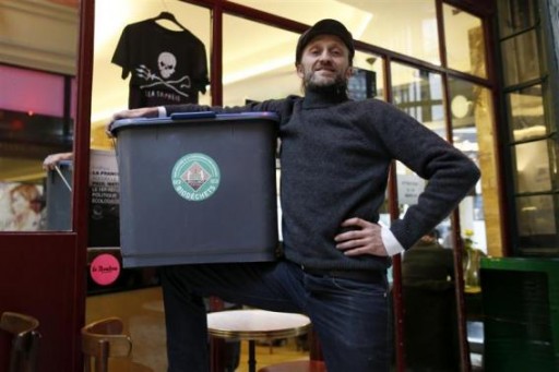 Stephan Martinez, owner of Le Petit Choiseuil bistrot, poses with a garbage container to collect food waste in Paris