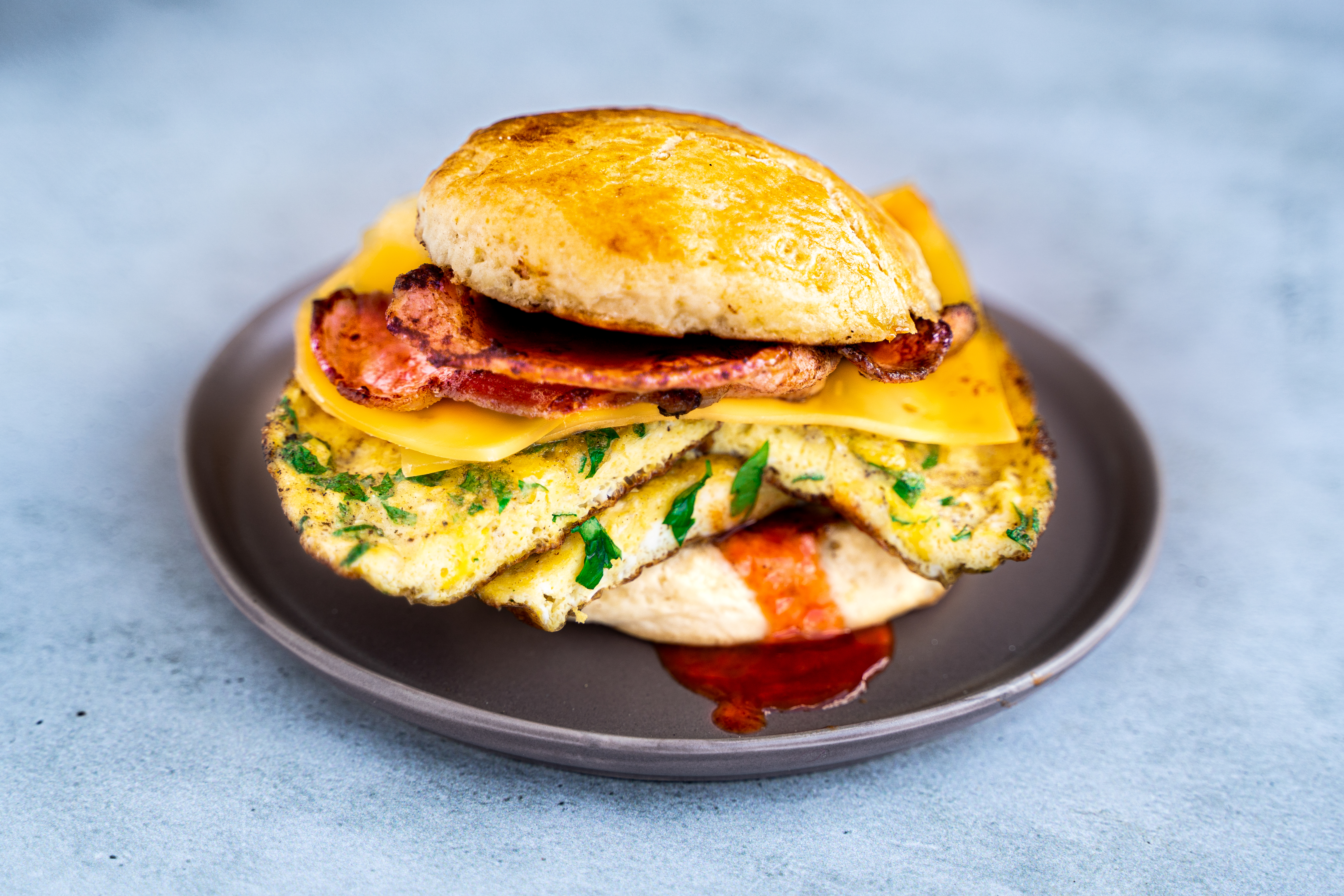 Breakfast sandwich op een scone met spek, kaas en omelet